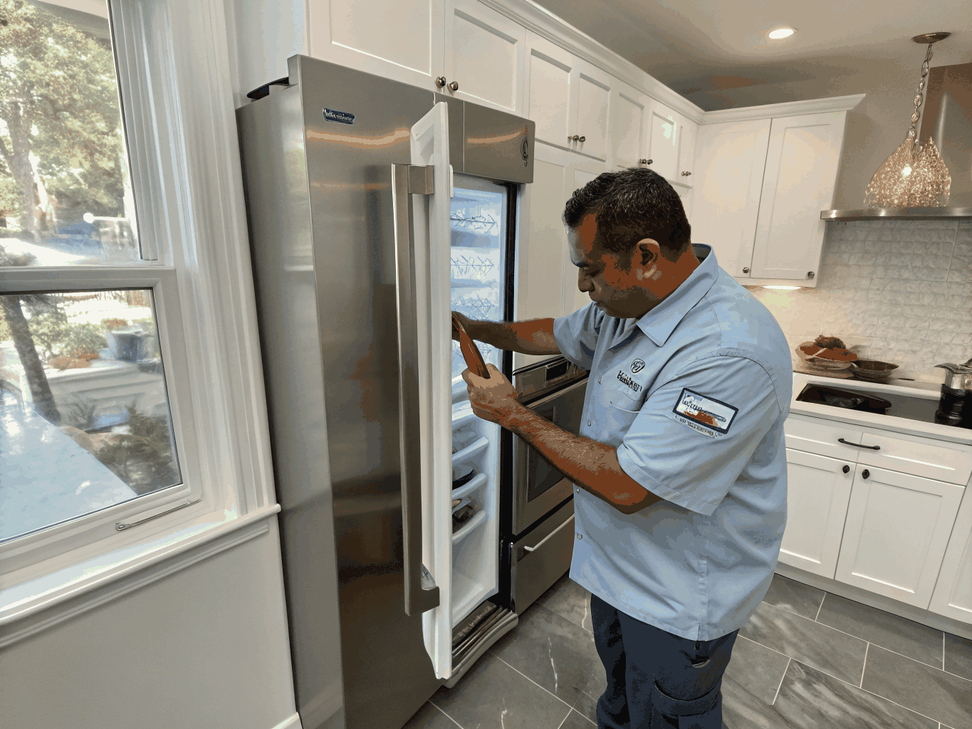 Technician repairing high-end refrigerator in a Vinings home kitchen